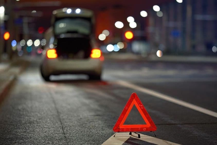 Defektes autó a m3 sztrádán éjjel, piros háromszög kocsi mögött.