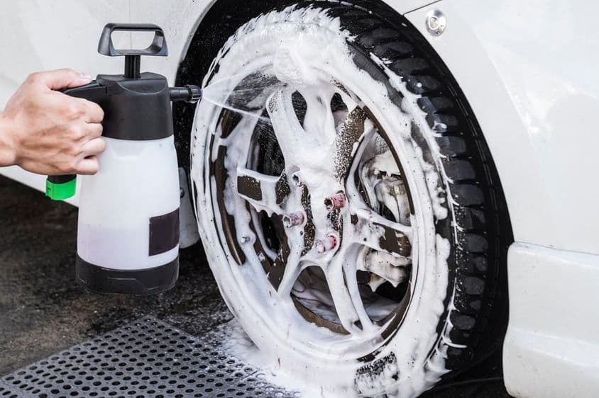 Egy férfi kézi pumpás autó habszórót használ.