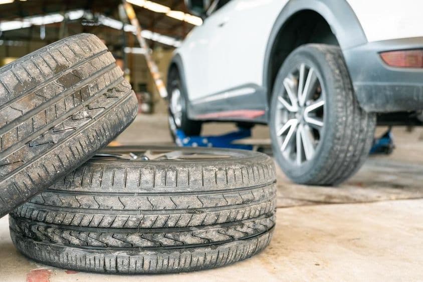 Gumiszerelő műhely és régi autóabroncs cseréje az autón.