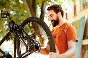 Férfi speciális szerszámokat használva karbantartja és javítja a kerékpáralkatrészeket a szabadban.