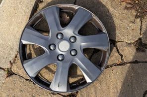 Ezüst autó keréktárcsa betonon pihen.