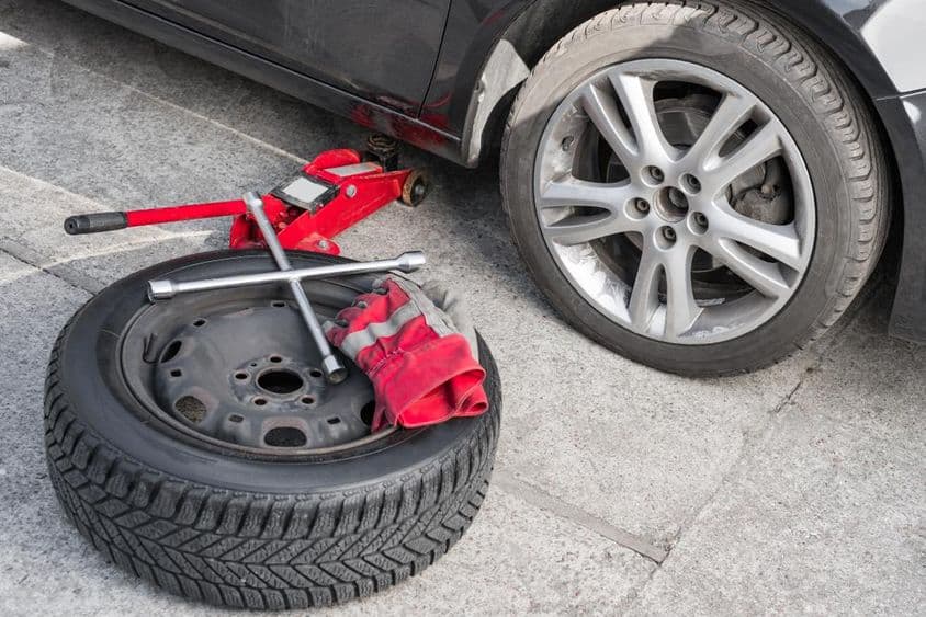 Téli kerék nyári gumiabroncsokkal felszerelt autó mellett.