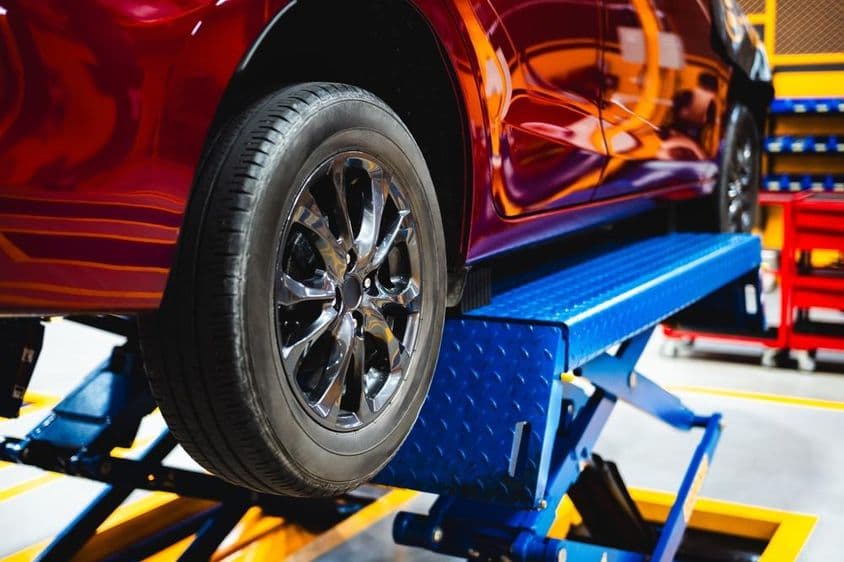 Egy kocsit emelnek fel az emelővel.