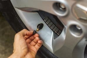 Kézzel felhelyezve a szelepsapkát az autó gumiabroncsára.