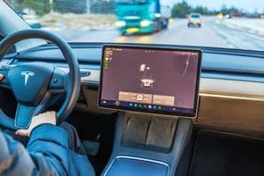 Egy nő Tesla Model Y-t vezet téli úton.