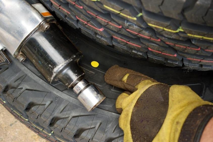 Kéz egy színes pontra mutat az új gumiabroncson.