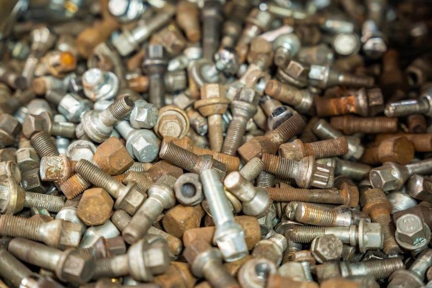 Különböző autókerék anyák gyűjteménye szétszórva egy felületen.