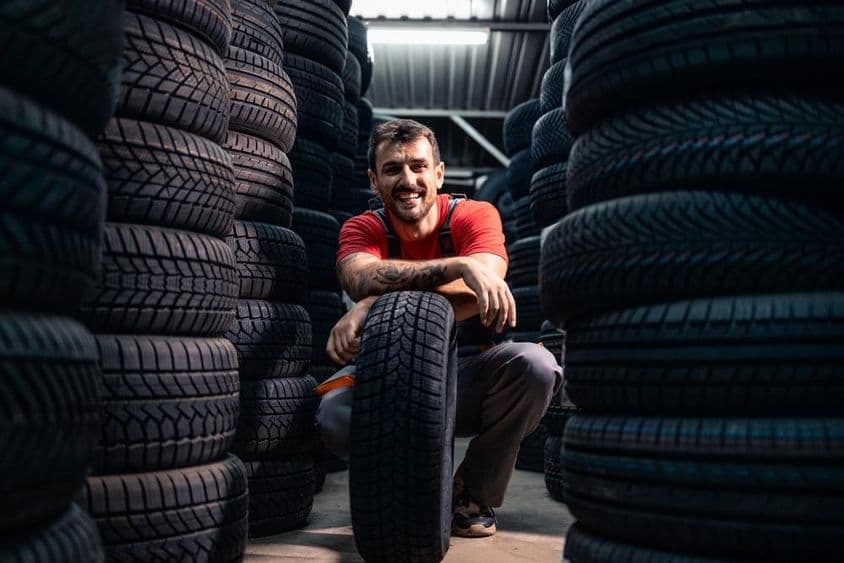 Egy munkás új gumiabroncsokat válogat a raktárban.