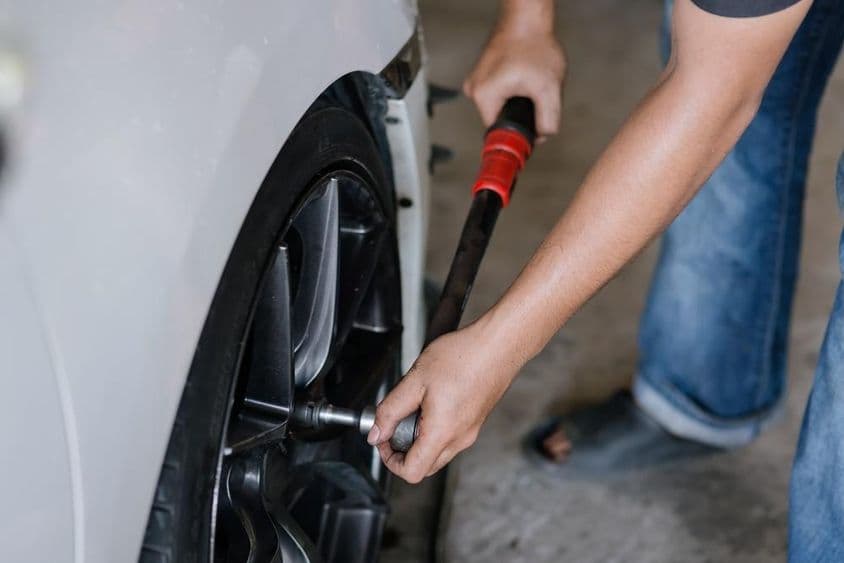 Profi szerelő gondosan meghúz egy autó kerékanyáját.