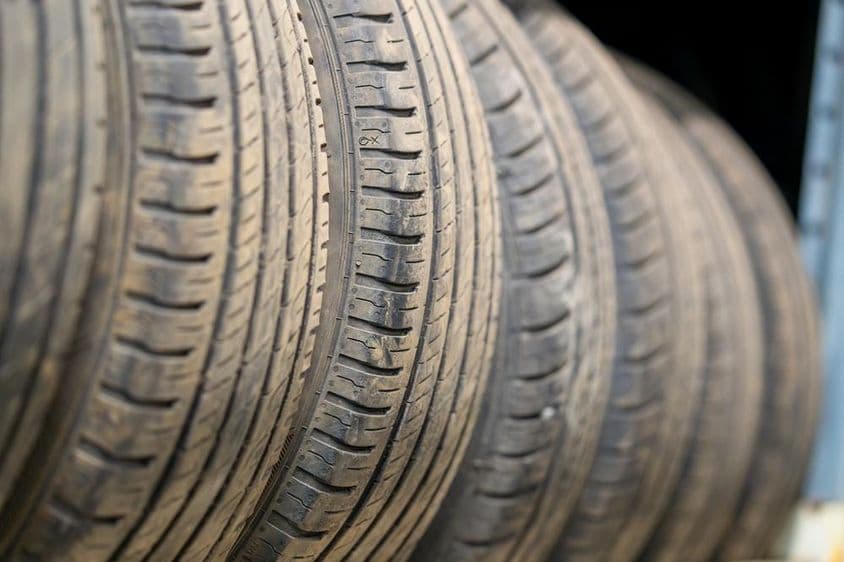 Használt autóabroncsok sora, amelyek futófelület-kopási mintázatokat mutatnak.