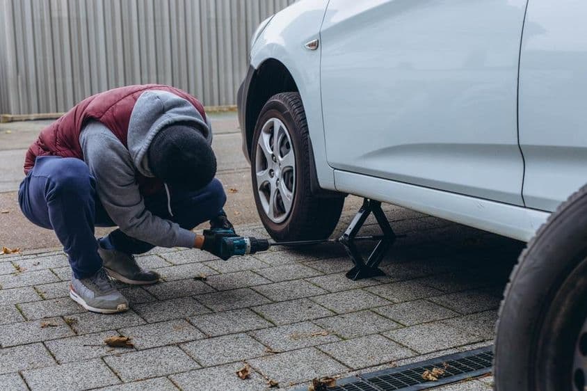 Egy férfi felemeli az autóját a kereékcseréhez