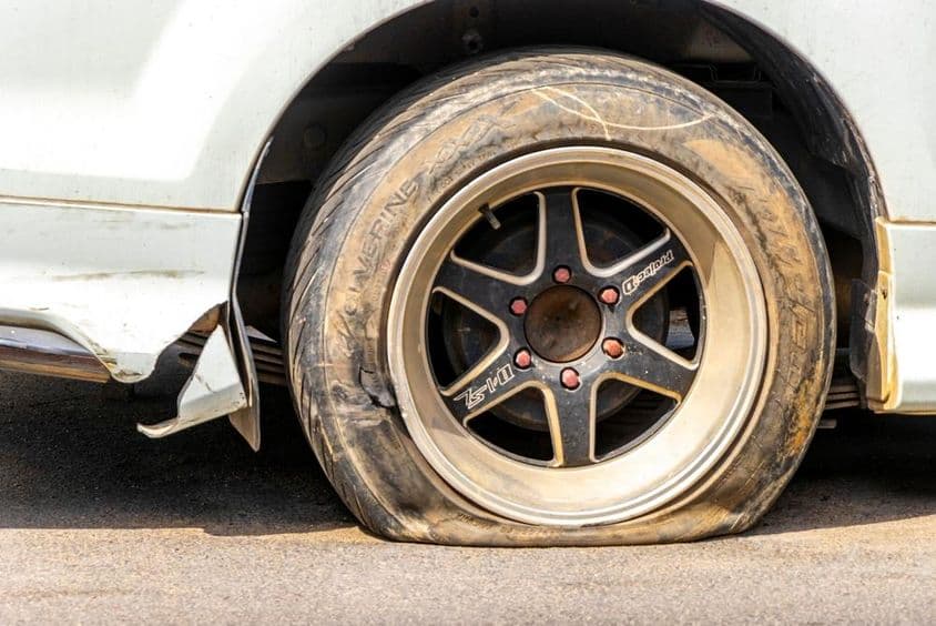 Lapos autógumi fekszik aszfaltozott úton trópusi környezetben