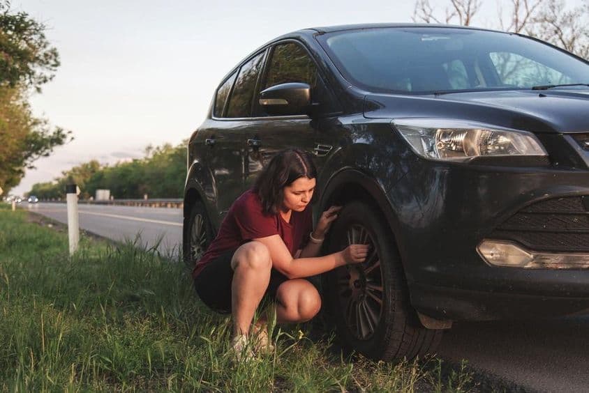 A defektet ellenőrző nő az út szélén